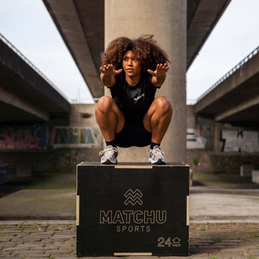 An athlete in MATCHU kit crouched on top of the plyo box under a bridge
