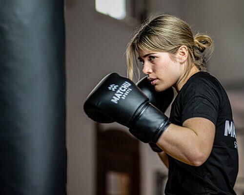 A boxer in MATCHU gloves next to a heavy bag