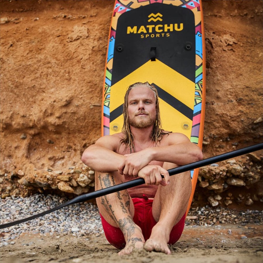 Paddler sitting in front of the Deluxe board on the beach